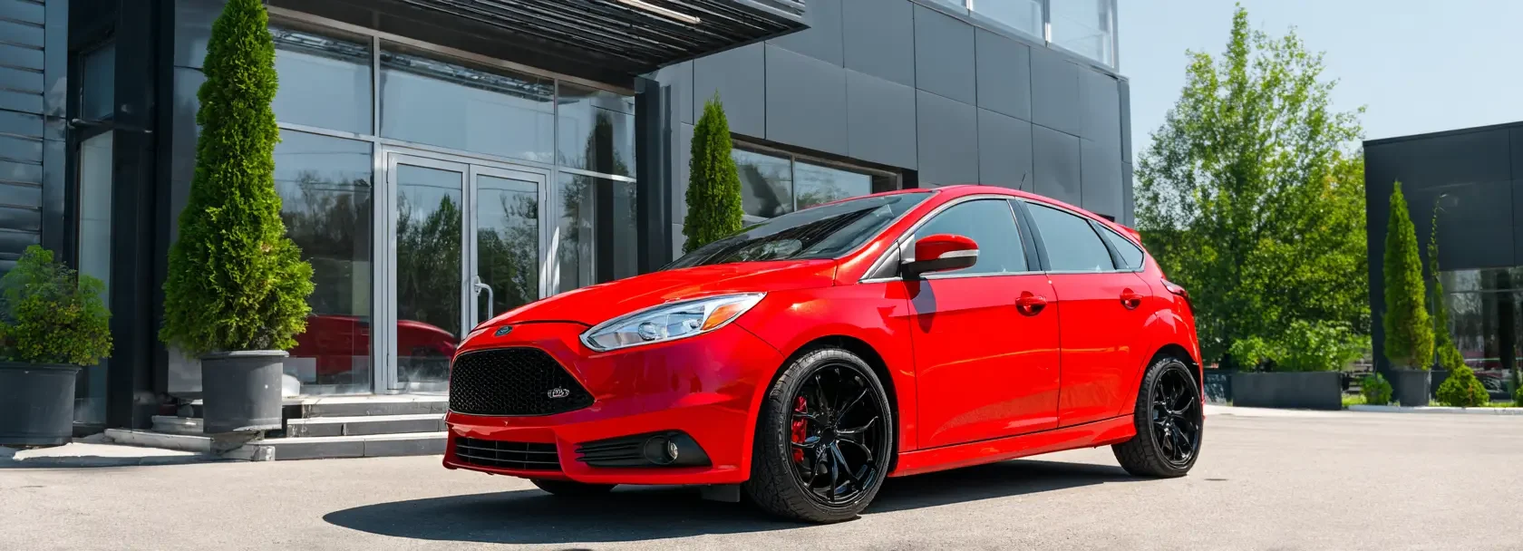a_shiny_red_hatchback_car_parked_outside